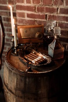 an old fashioned radio and cigars are on top of a barrel next to a candle