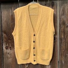 This is a beautiful wool/wool blend vest from the 1960s The original tag is no longer there  It fits like a men's extra large, but please see measurements for the exact fit I absolutely adore this vest and it gives me Mister Rodgers vibes 🥰 It buttons up the front for closure and has two front pockets for your goodies I have not noticed any flaws! I love this color, it's such a happy color imo, it's like a golden yellow, a mellow yellow lets say. The first 4 pics depict the actual color better then the rest of the photos just fyi  measurements as follows: pit to pit lying flat is 24" inches  length is 27" inches  I ship priority mail with tracking! Thanks for looking :) Retro Sleeveless Sweater Vest For Fall, Retro Sleeveless Fall Outerwear, Retro Sleeveless Outerwear For Fall, Vintage Wool Vest For Fall, Vintage Wool Sleeveless Sweater Vest, Classic Wool Sweater Vest For Fall, Retro Fall Vest With Pockets, Vintage Sleeveless Wool Sweater Vest, Vintage Sleeveless Sweater Vest For Fall