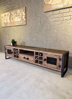 a large wooden entertainment center with metal handles and drawers on the sides, in front of a brick wall