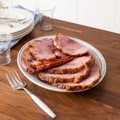 slices of ham on a plate next to silverware