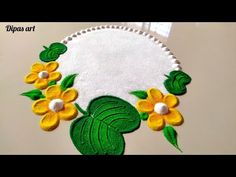 a close up of a white table cloth with yellow flowers and green leaves on it