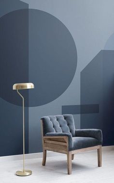 a chair with a lamp in front of it and a blue wall behind the chair