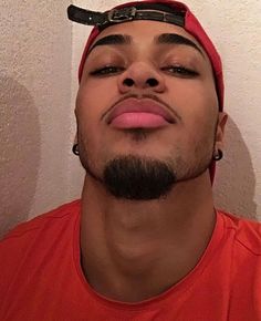 a man with his eyes closed, wearing a red shirt and black headband is looking up at the camera