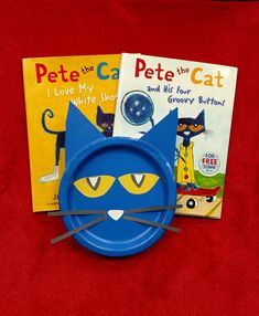 a blue plate with a cat face on it next to two children's books