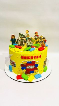 a yellow lego cake topped with lots of toy figurines on top of it