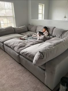 a person laying on top of a couch with a book in their hand and looking at it