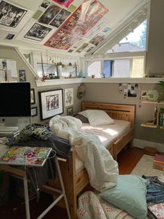 a bed sitting under a window next to a computer desk with a monitor on top of it