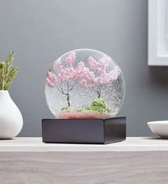 a snow globe sitting on top of a table next to a vase with flowers in it