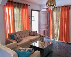 a living room filled with furniture and orange drapes