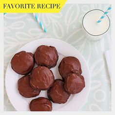 chocolate covered cookies on a plate next to a glass of milk