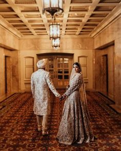 a bride and groom holding hands in an ornate hallway