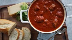 a bowl of meatballs and bread on a cutting board