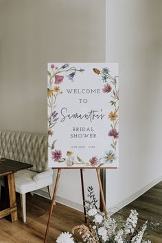 a welcome sign sitting on top of a wooden easel next to a white bench