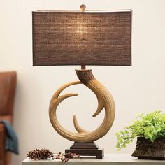 a table lamp sitting on top of a wooden table next to a potted plant