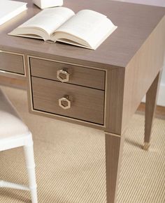 an open book sitting on top of a wooden desk next to a chair and table