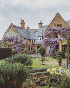 a large house with lots of purple flowers in the front yard