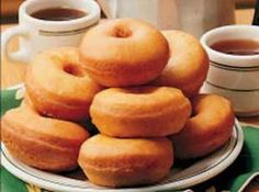 a stack of doughnuts sitting on top of a plate next to two cups of coffee