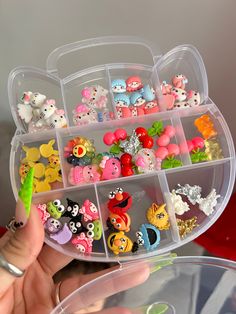 a person holding a plastic container filled with lots of small toys