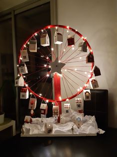 a ferris wheel decorated with christmas lights and presents on it's display stand in front of a window