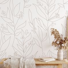 a vase with flowers on a wooden table next to a mirror and wallpaper design