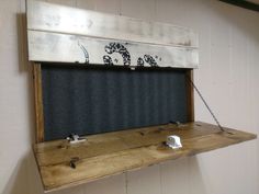 a wooden shelf with a chalkboard attached to the wall and some hooks on it