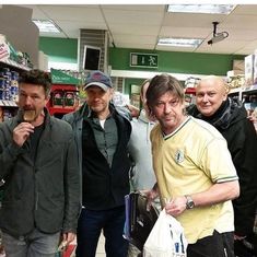 three men are standing in a store with one holding a bag and the other looking at something