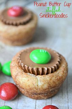 two peanut butter cupcakes with green and red candies on the table next to them