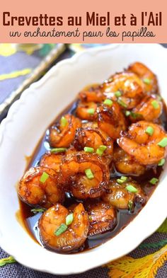 a white bowl filled with shrimp and sauce on top of a blue table cloth next to a