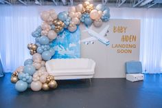 an airplane balloon arch is displayed in front of a backdrop with blue, white and gold balloons