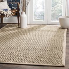 a large rug in the middle of a room with a chair and vase on the floor