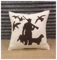 a pillow with a silhouette of a man holding a dog and birds