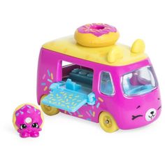 a pink toy bus with donuts on top and a small figure next to it