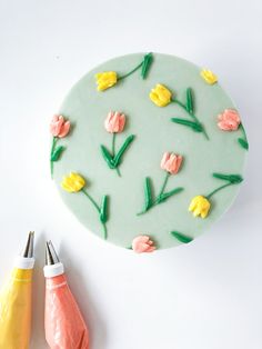 a cake decorated with flowers and crayons next to some crafting supplies on a white surface