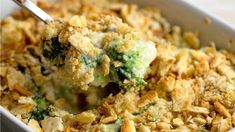 a casserole dish filled with broccoli and other toppings is being held by a fork