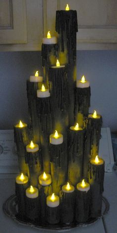 there is a very tall candle holder made out of logs and lit up with candles