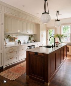 a large kitchen with an island in the middle and two lights hanging from the ceiling