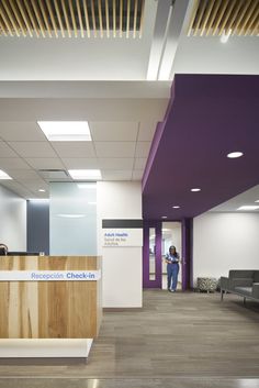 an office lobby with purple and white walls, wood flooring and a reception desk