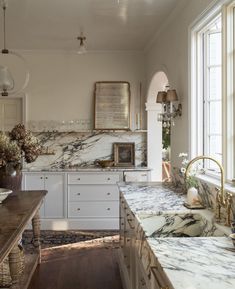 a large kitchen with marble counter tops and white cabinets, along with an arched window