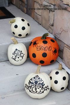 four painted pumpkins sitting on the steps with black and white designs, one is orange