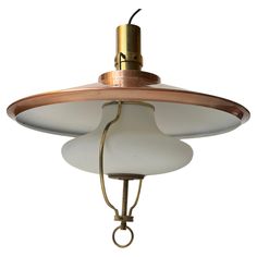 an old fashioned light fixture with a white glass shade on the top and gold trim