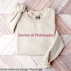 **EMBROIDERED DESIGN** Looking for a unique and personal gift for a recent or soon-to-be PhD graduate? Look no further than this customizable PhD sweatshirt! Our sweatshirts are made from high-quality materials and come in a range of sizes to fit any body type. Plus, with the option to personalize the name on the sweatshirt, it's a one-of-a-kind gift that's sure to be treasured for years to come. To order, simply choose your preferred size and color, then enter the name you want to appear on the sweatshirt. We use only the highest-quality materials and printing techniques to ensure a long-lasting, vibrant print that won't fade or peel. This sweatshirt is perfect for anyone who's proud of their academic accomplishments and wants to show it off in style. Please take a moment to read carreful Phd Shirt, Phd Graduate, Phd Humor, Phd Gifts, Gift Embroidery, Doctor Graduation, Embroidery Shirt, Phd Student, Graduation Shirts