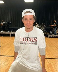 a man in white shirt and headband standing on wooden floor next to microphones