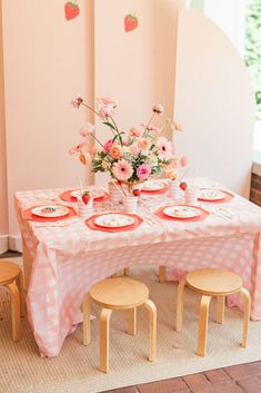 the table is set with plates and pink flowers