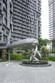 a sculpture in the middle of a courtyard with buildings in the backgrouds