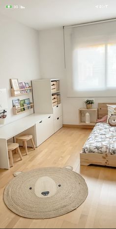 a bedroom with white walls and wooden floors has a large rug on the floor next to the bed