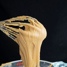 a whisk is being used to make peanut butter frosting on a spoon