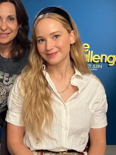 two women standing next to each other in front of a blue background