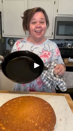 a woman in the kitchen holding a pan with food on it and making a cake