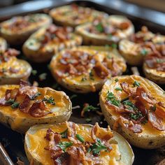 baked potatoes topped with bacon and cheese on a baking sheet, ready to be eaten