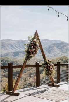 an outdoor ceremony setup with flowers and greenery on the top of a wooden structure